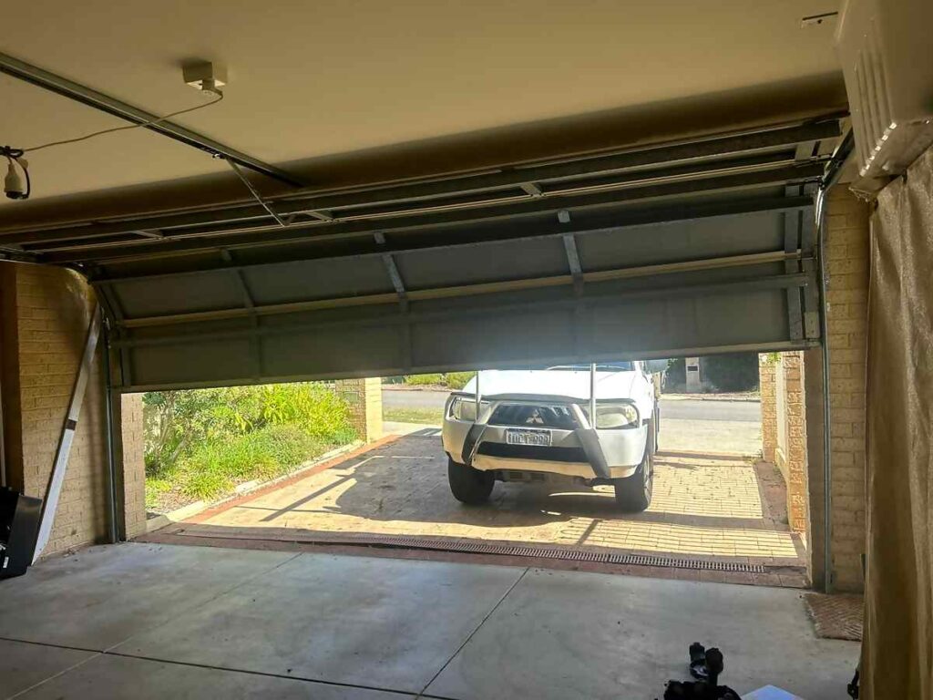 Sectional garage door part open showing tracks and opener rail in Palmyra, Perth
