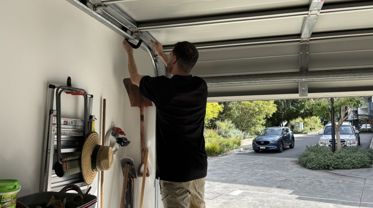 A professional technician inspecting a garage door track and components during the initial diagnosis of a repair issue.
