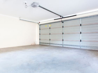 Newly installed double garage door with a smooth concrete floor and an automatic garage door opener mounted on the ceiling.