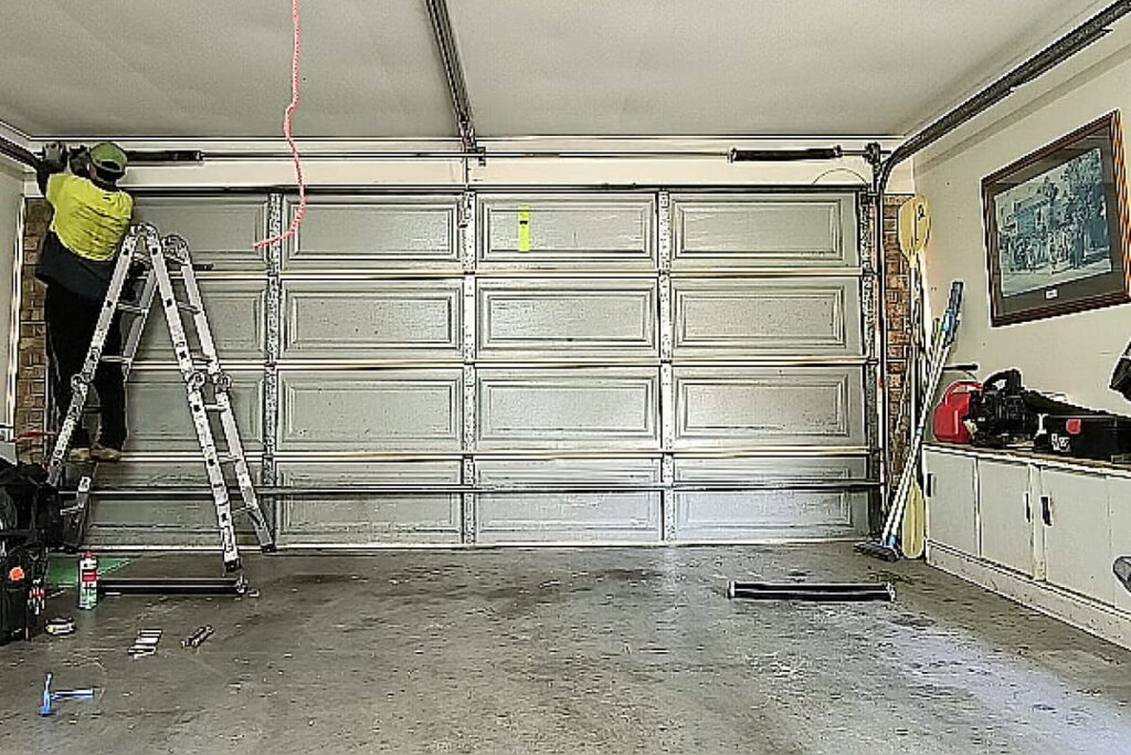 Technician replacing torsion springs on a double sectional panel lift door in Arundel, Gold Coast