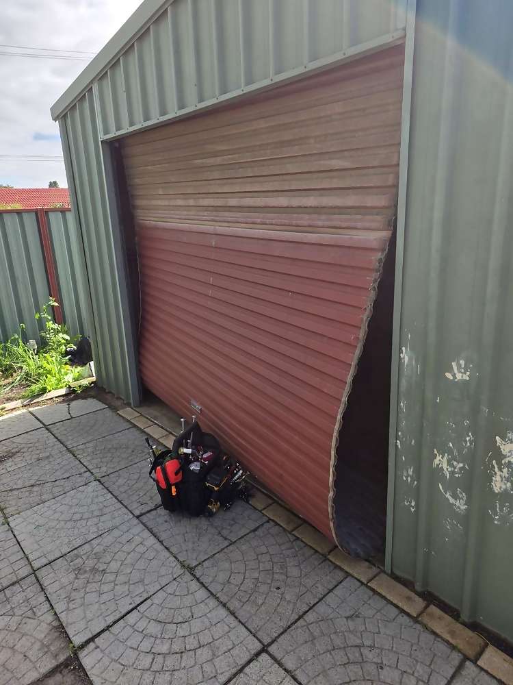 Roller door pulled out of its guide and bowed outward on a shed in Armadale, Perth