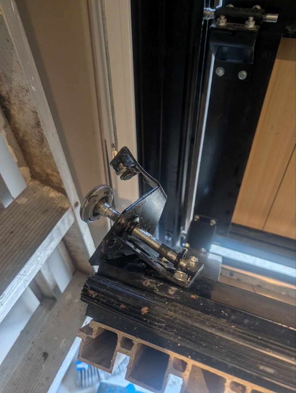 Close-up of the bottom corner bracket and lift cable attachment point on a sectional door during realignment in Elwood, Melbourne.