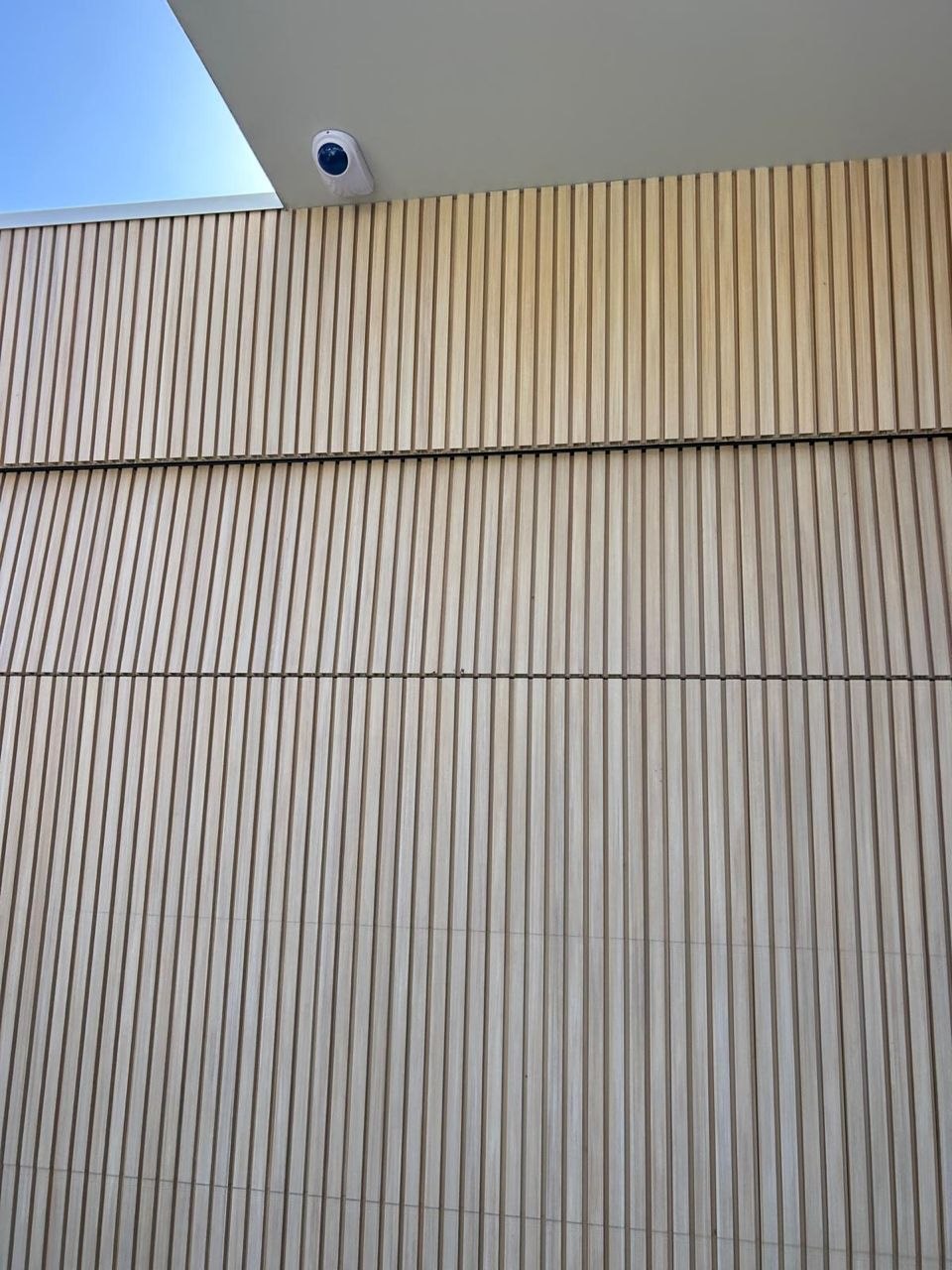 Exterior view of a residential property showing a timber-clad sectional garage door with a security camera mounted above in Elwood, Melbourne.