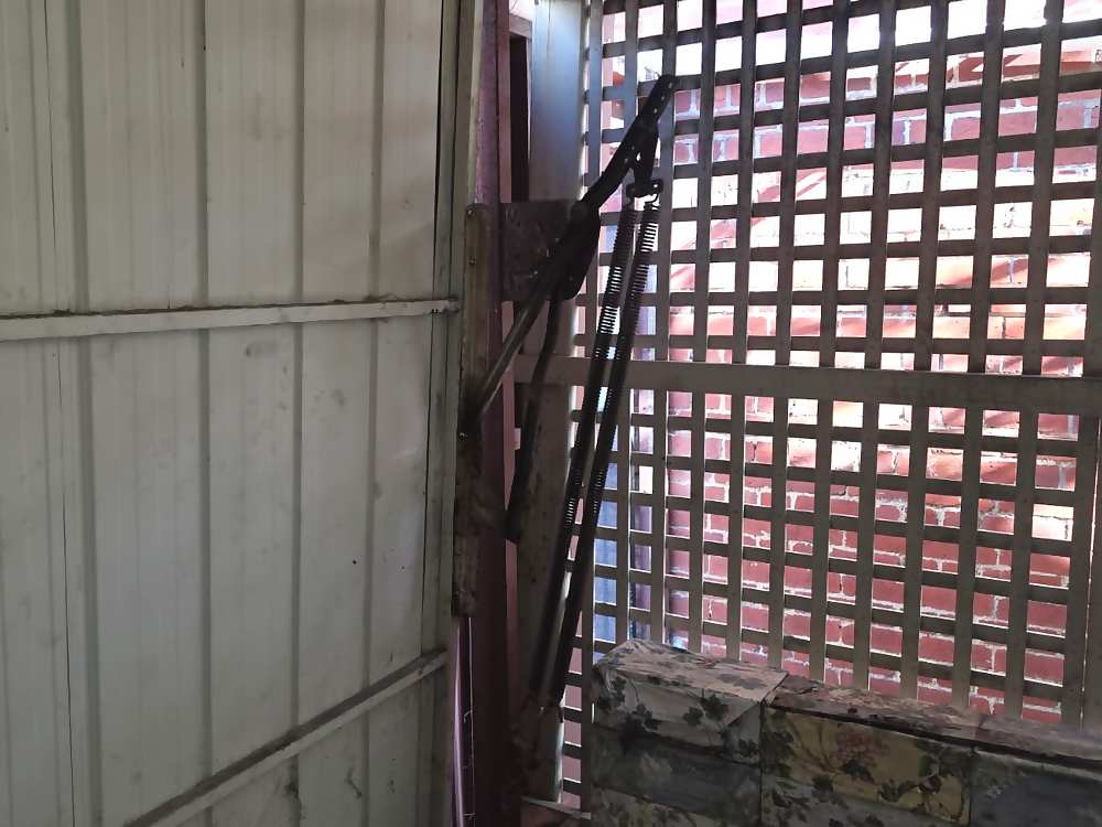 Tilt door arm and spring connected to a bracket on a garage door